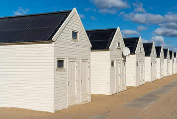 Fototapeta na wymiar Row of white wooden beach houses with solar panels at seaside resort Katwijk aan Zee