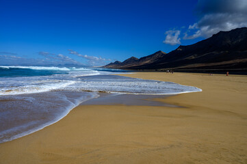 View on difficult to access golden sandy Cofete beach hidden behind mountain range on Fuerteventura, Canary islands, Spain