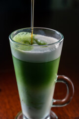 Glass of green Matcha tea made from finely ground powder of specially grown and processed green tea leaves consumed in East Asia with whipped milk