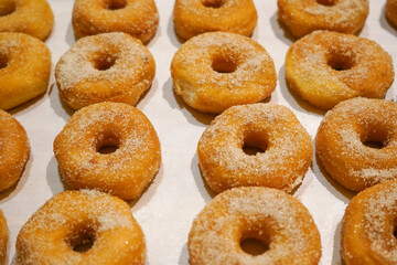 Donuts with sugars displayed in shelf.