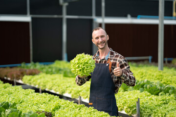 Portrait of caucasian male farmer working in hydroponics farm, standing and smiling to the camera.