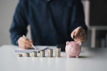 Businessman putting coins into piggy bank for saving money concept.