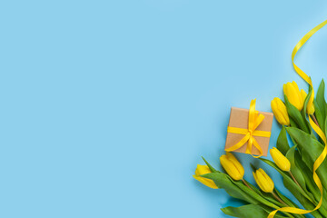 Yellow tulip flowers and gift box on blue background. Women's day or Mother's day concept. Flat...