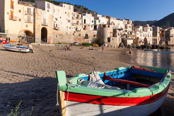 Fototapeta na wymiar Cefalù, Palermo. Spiaggia del porticciolo con barca da pesca