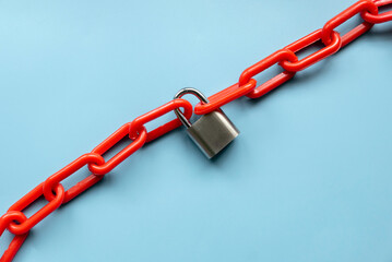 Safety concept. Red chain and padlock on blue background.