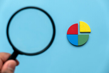 Quarterly report concept.Company financial report.Business charts. Colorful quarter wooden pie chart pieces with magnifying glasses. 