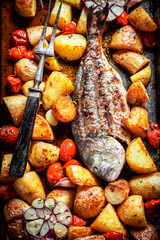 Homemade sea bream with potatoes and tomatoes on grill
