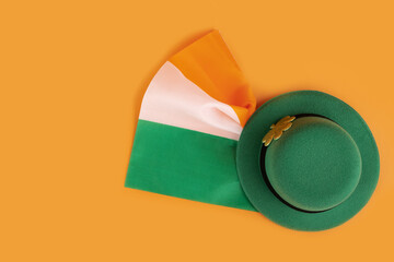 green irish leprechaun hat with gold clover and irish flag on orange background, saint patrick day banner, irish holiday card, top view