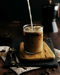 Taza transparente de café con leche y hielo sobre una tabla de madera