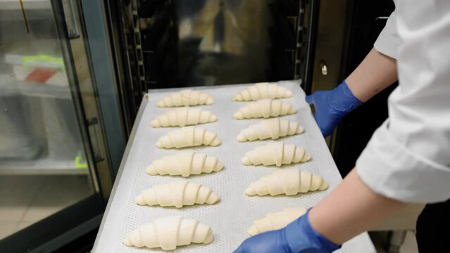Kitchen in a bakery - the chef sends a baking sheet with croissants to the combi oven