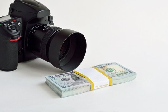  A pack of hundred-dollar US banknotes with a camera. The concept of making money from photos