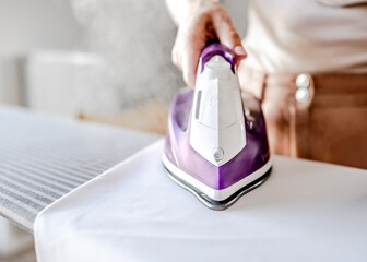 Girl hand using iron for wrinkled clothes