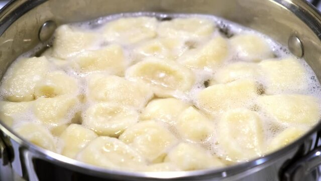 Lazy dumplings from curd dough are boiling in the pan. Top view. A traditional dish of Russian and Ukrainian cuisine. Tasty breakfast. Homemade food. Halushki.