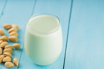 Pistachio milk in glass on blue boards. Vegan nutty plant based milk. Diet milk, vegetarian food