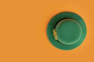 green irish leprechaun hat with gold clover on orange background