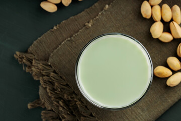 Pistachio milk in a glass on a dark green background. Healthy lactose-free pistachio milk and pistachios. Vegan nutty plant based milk. Top view. Copy space