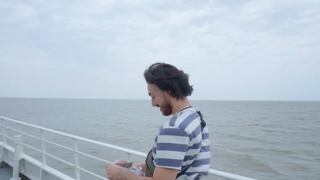 Young latin man on the deck of a ferry talking to the cameraman as the wind blows. 4k video.