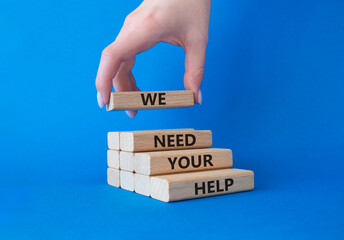 We need your help symbol. Wooden blocks with words We need your help. Businessman hand. Beautiful blue background. Business and We need your help concept. Copy space.