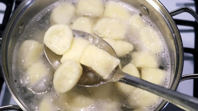 Lazy dumplings from card dough are boiling in the pan. Top view. A traditional dish of Russian and Ukrainian cuisine. Tasty breakfast. Homemade food. Halushki. Mixing with spoon. Ready meal.