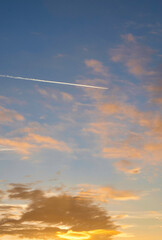 clouds in the sky at sunrise and the trail of a passing plane