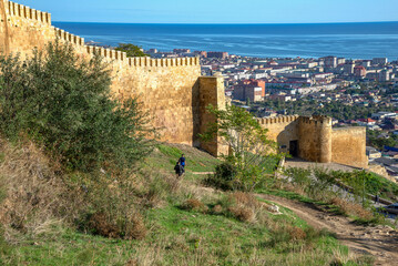 Fototapeta premium Tourists at the walls of the old fortress. Derbent, Republic of Dagestan, Russia