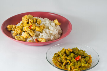 stir-fried bitter melon with sliced tempeh and white rice with sliced tofu cooked dry with chilies served in a small plate isolated on a white background