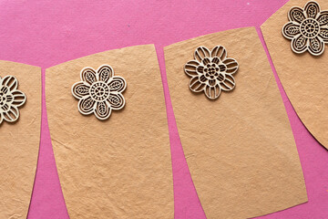 several sand-brown/yellow cards with rough texture and cut wooden floral/spirals on pink