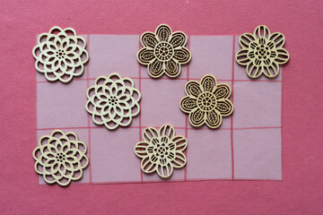 wooden floral decorative objects on tracing paper with grid on rough pink scrapbook paper