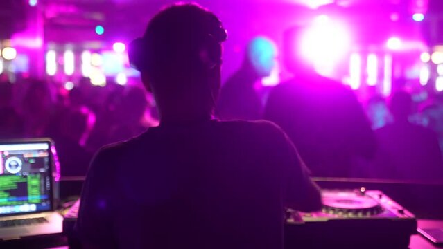 DJ putting on headphones, controlling the mixing desk