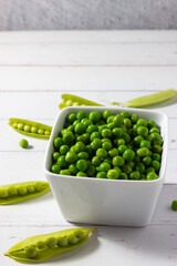 Healthy living. Good nutrition. Good eating habits. Fresh peas in a bowl on a white wooden background.