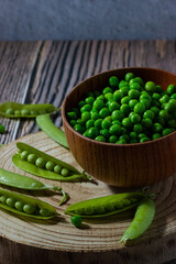 Close-up of fresh peas in a bowl and wooden background. Healthy food concept.