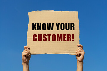 Know your customer text on box paper held by 2 hands with isolated blue sky background. This...