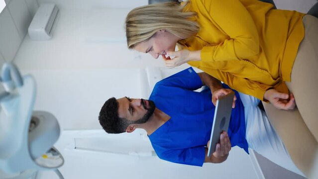 Dentist doing a consultation with digital tablet with his patient. Vertical footage.
