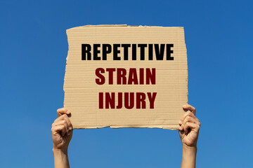 Repetitive strain injury text on box paper held by 2 hands with isolated blue sky background. This message board can be used as business concept to inform audience about ergonomics. and RSI