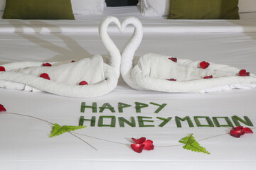 Luxury hotel bedroom interior with honeymoon decoration, Towel swans and rose flowers on the bed