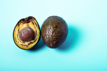 Rotten avocado, overriped, bad avocado. Half sliced fruit, freegan food concept, blue background. The theme of careful consumption and care for the environment. Copyspace