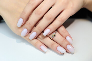 Gentle nude manicure on her nails. Classic bridal nail design.