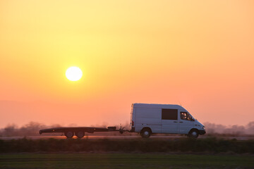 Tow truck vehicle with car carrier trailer driving on highway in evening