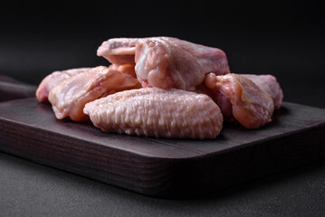 Raw chicken wings with salt, spices and herbs on a wooden cutting board