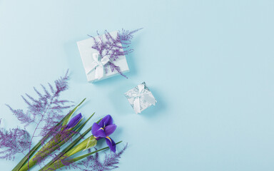 Mother's or Women's Day mock up card from spring irises flowers. Greeting card with empty place for text and gift boxes for International Mothers Day on blue background. Flat lay, top view.