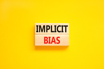 Implicit bias symbol. Concept words Implicit bias on wooden block. Beautiful yellow table yellow background. Business psychology implicit bias concept. Copy space.