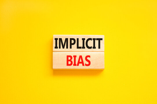 Implicit bias symbol. Concept words Implicit bias on wooden block. Beautiful yellow table yellow background. Business psychology implicit bias concept. Copy space.
