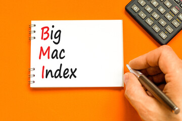 BMI big mac index symbol. Concept words BMI big mac index on white note on a beautiful orange...