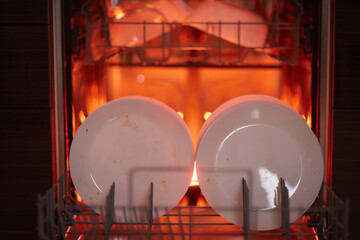 Clean plates after washing in the dishwasher. Close-up of the dishes placed in the dishwasher....