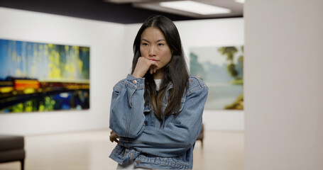 Portrait of 30s Asian female engaging with art at an exhibition. Modern fine arts museum. Model and...