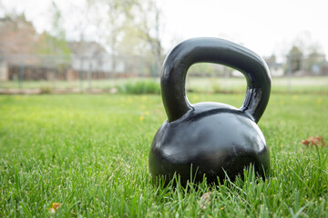 Fototapeta na wymiar heavy iron black kettlebell on green grass in backyard - outdoor fitness concept