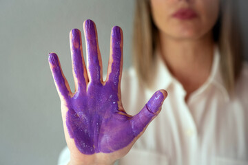 A woman shows a purple palm of hand as a symbol of the feminist movement for women's equality.