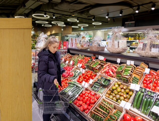 Woman buying vegetables(tomatoes and cucumbers) at the market