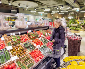 Woman buying vegetables(tomatoes and cucumbers) at the market