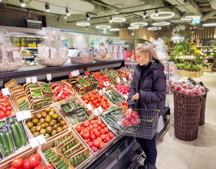 Woman buying vegetables(tomatoes and cucumbers) at the market
